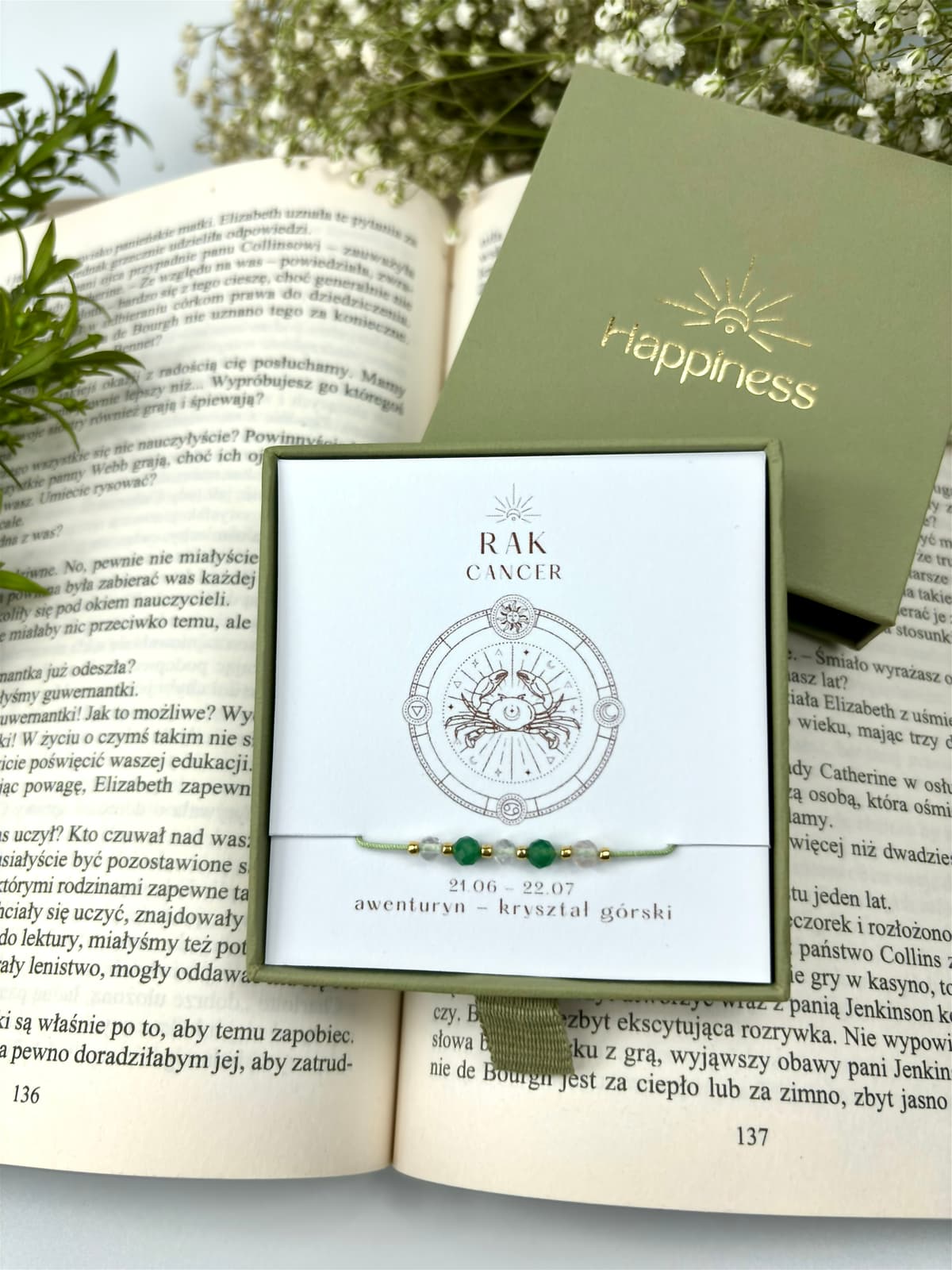 Bransoletka na jasnozielonym sznurku nylonowym z koralikami z kamieni naturalnych: zielonym awenturynem i przezroczystym kryształem górskim. Opakowana w pudełko w kolorze oliwkowym ze złotym logo Happiness.