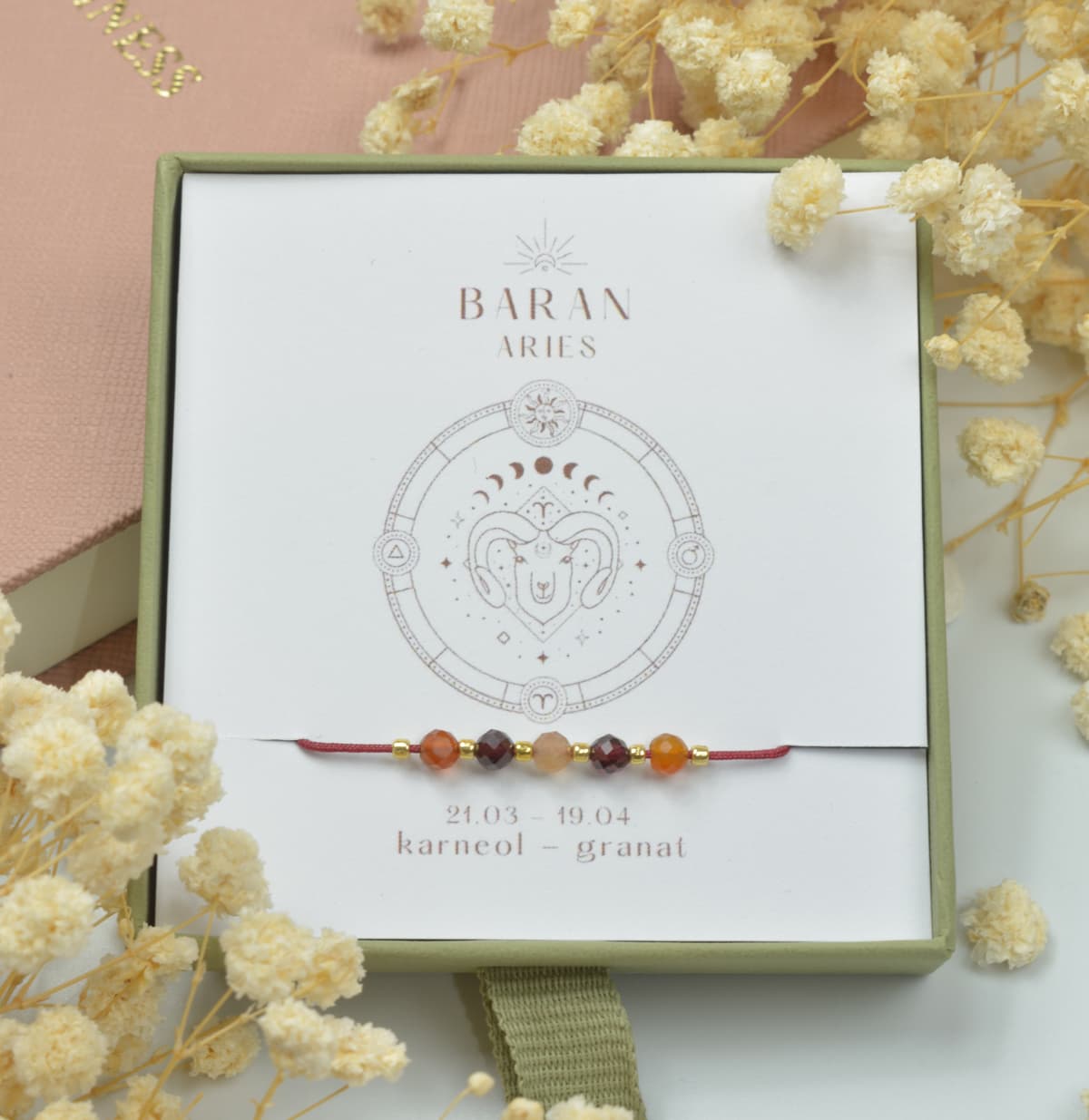 Bransoletka na czerwonym sznurku nylonowym z koralikami z kamieni naturalnych: pomarańczowym karneolem i ciemnoczerwonym granatem. Opakowana w pudełko w kolorze oliwkowym ze złotym logo Happiness.