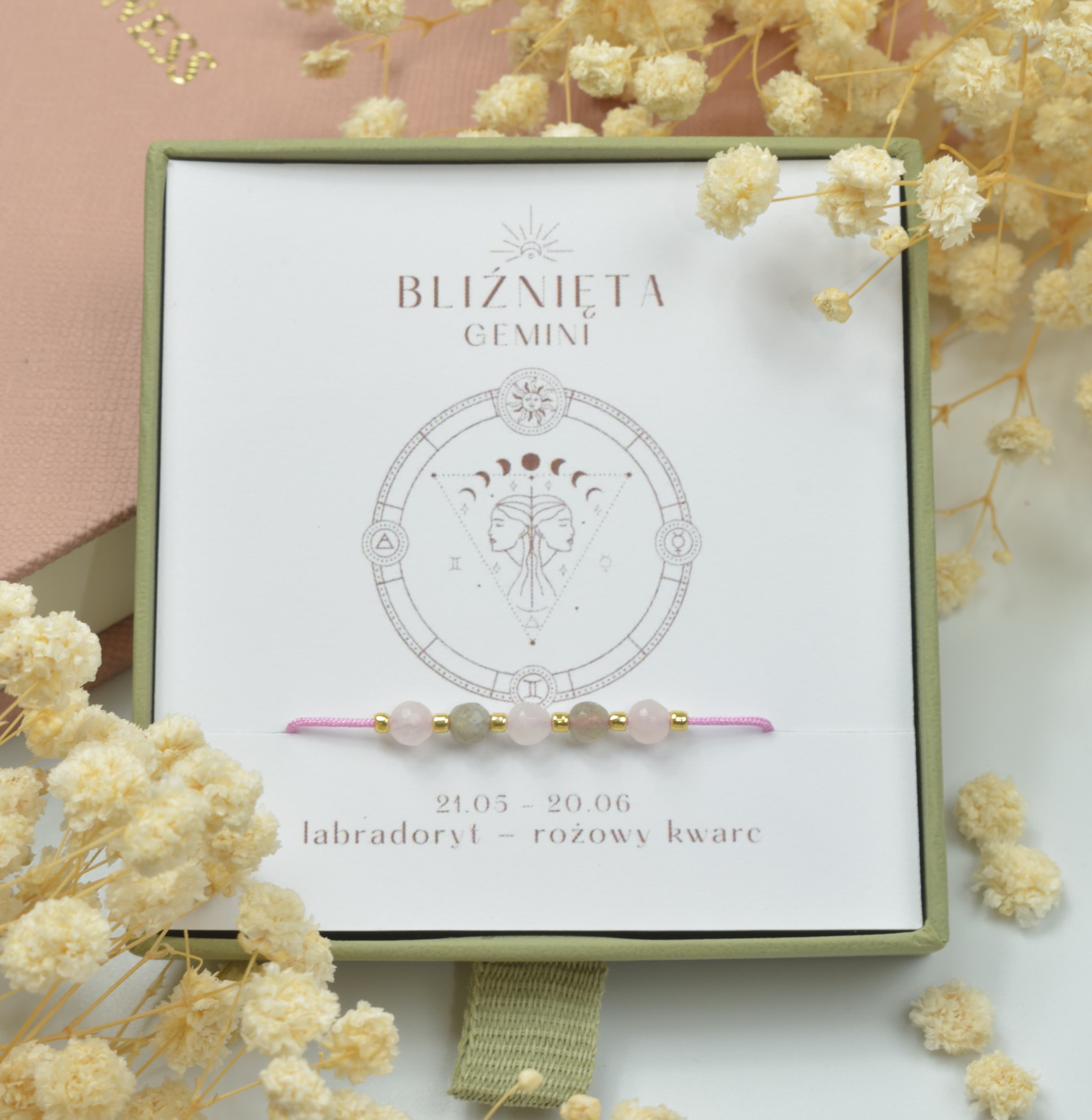 Bransoletka na różowym sznurku nylonowym z koralikami z kamieni naturalnych: szarym labradorytem i różowym kwarcem. Opakowana w pudełko w kolorze oliwkowym ze złotym logo Happiness.