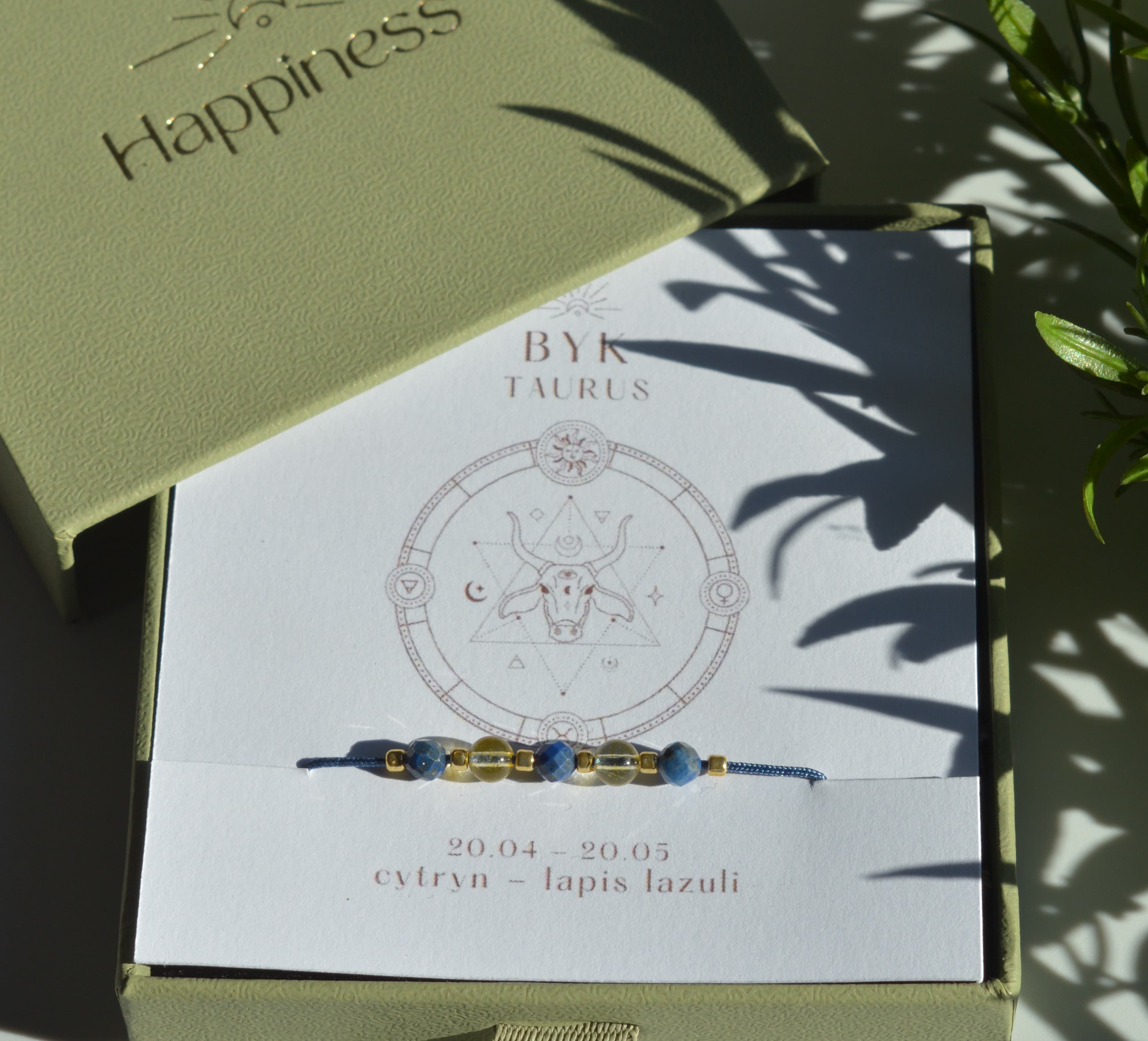 Bransoletka na granatowym sznurku nylonowym z koralikami z kamieni naturalnych: żółtym cytrynem i ciemnoniebieskim lapis lazuri. Opakowana w pudełko w kolorze oliwkowym ze złotym logo Happiness.