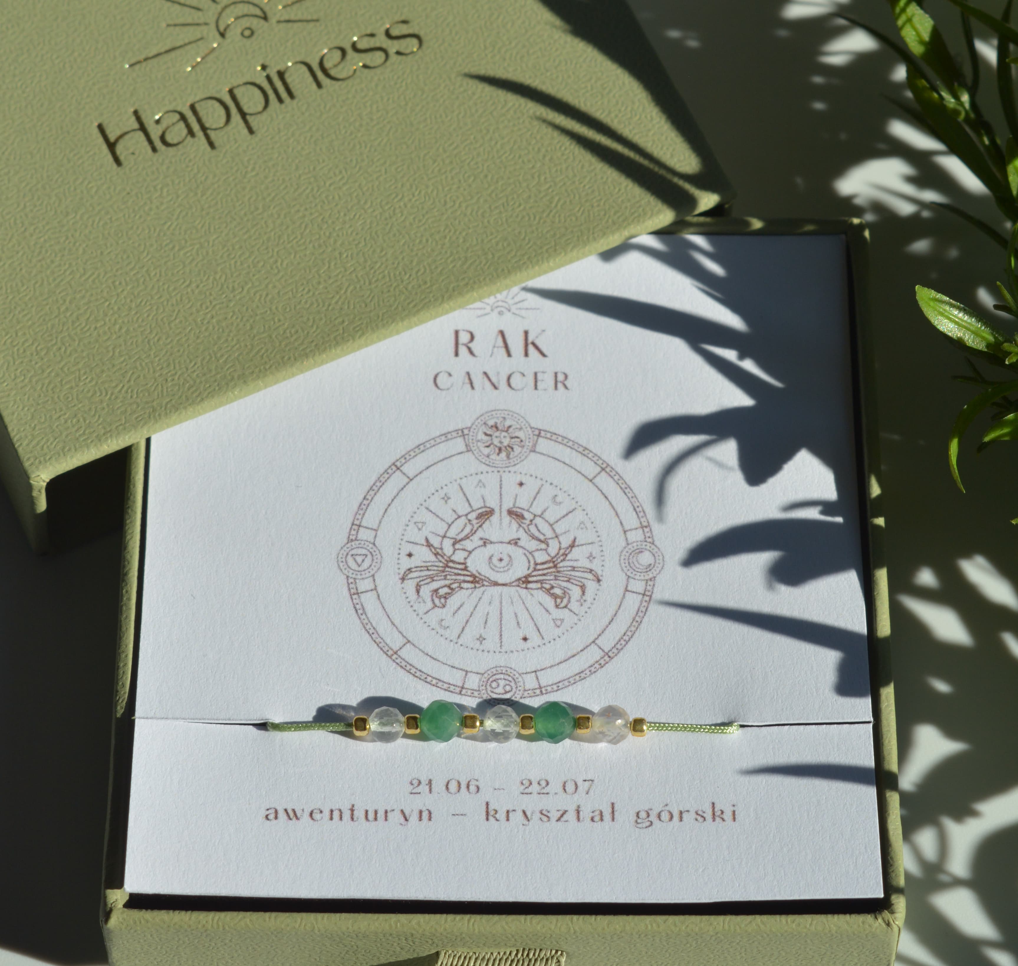 Bransoletka na jasnozielonym sznurku nylonowym z koralikami z kamieni naturalnych: zielonym awenturynem i przezroczystym kryształem górskim. Opakowana w pudełko w kolorze oliwkowym ze złotym logo Happiness.