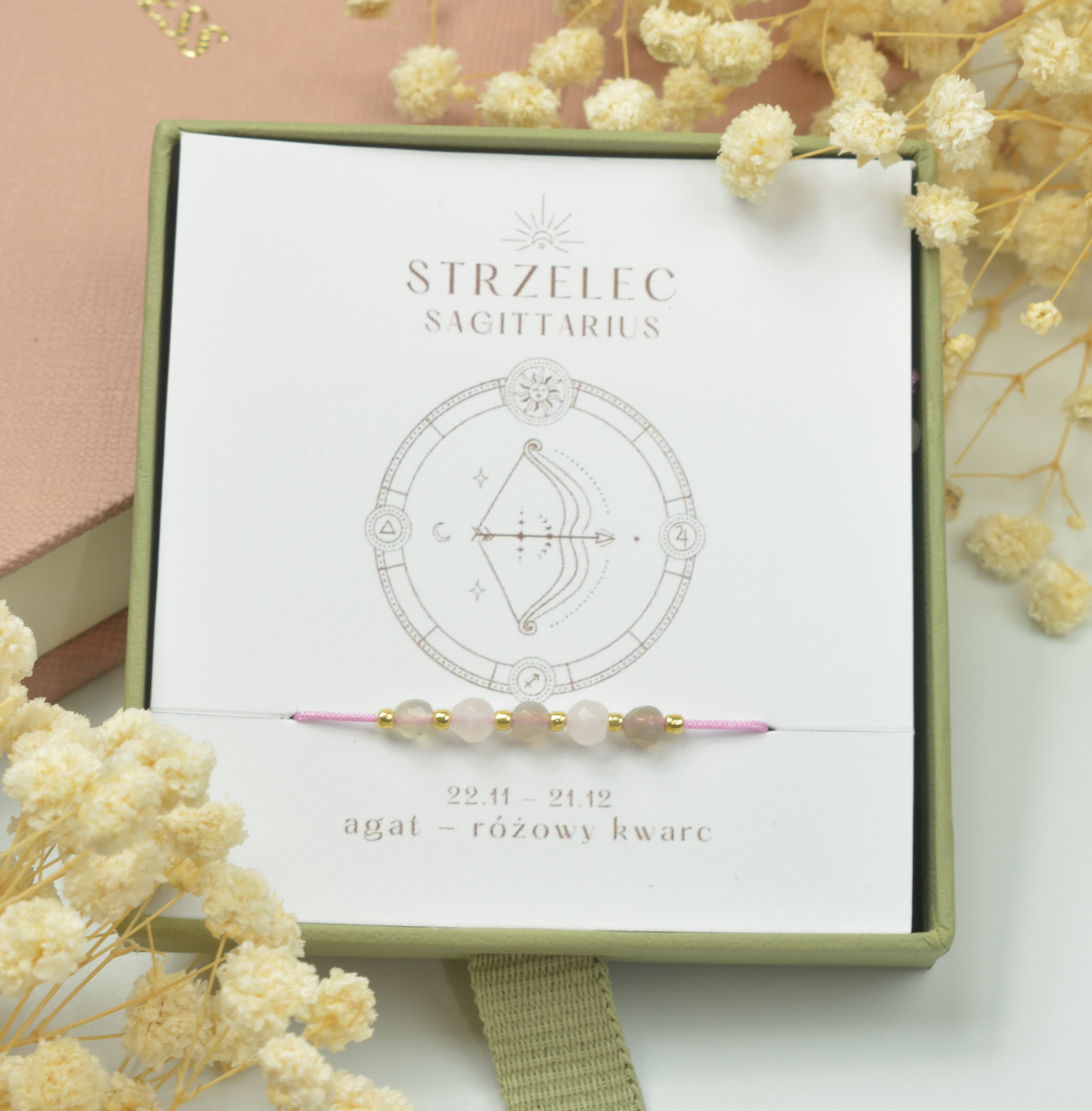 Bransoletka na różowym sznurku nylonowym z koralikami z kamieni naturalnych: szarym labradorytem i różowym kwarcem. Opakowana w pudełko w kolorze oliwkowym ze złotym logo Happiness.