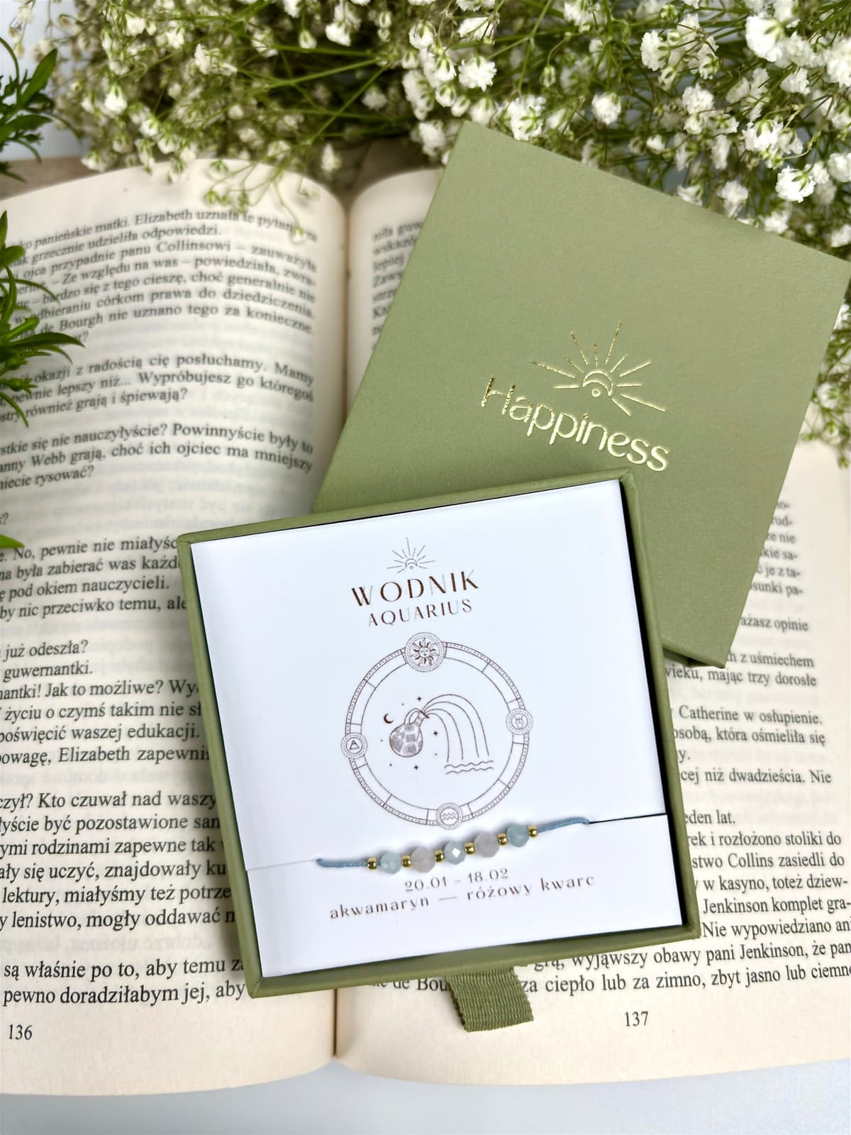 Bransoletka na błękitnym sznurku nylonowym z koralikami z kamieni naturalnych: błękitnym akwamarynem i różowym kwarcem. Opakowana w pudełko w kolorze oliwkowym ze złotym logo Happiness.